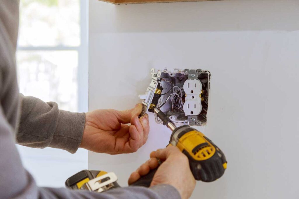Worker installing outlet, Source Electric Services